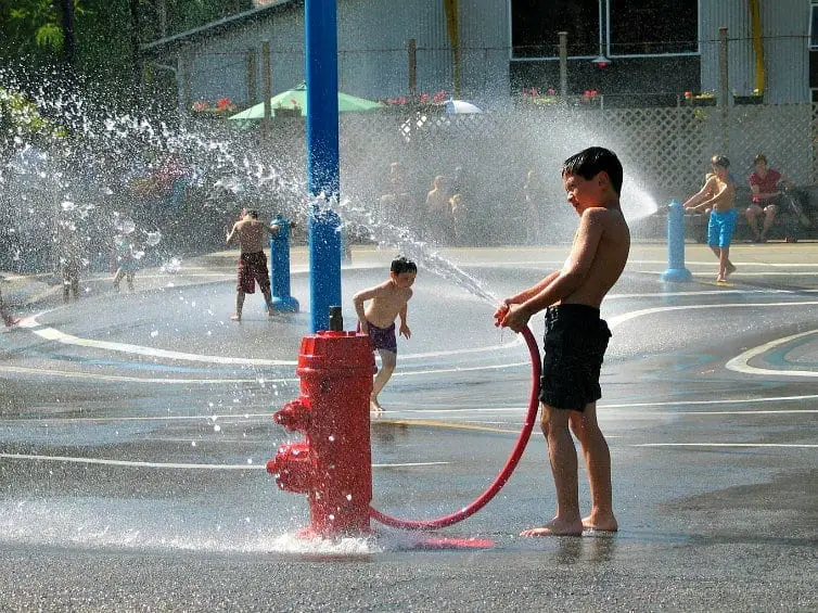 child playing with water hose at granville island