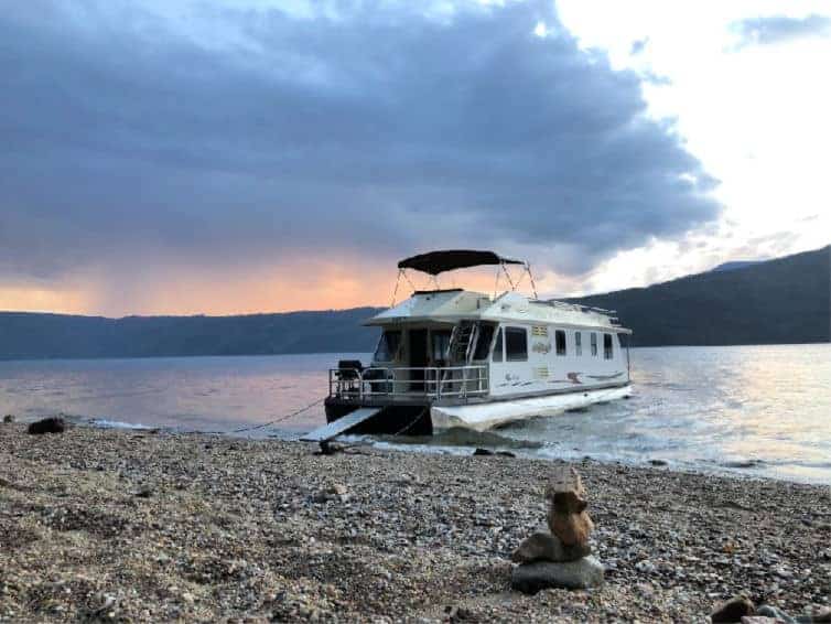 houseboat anchored on the shore of shuswap lake at dusk