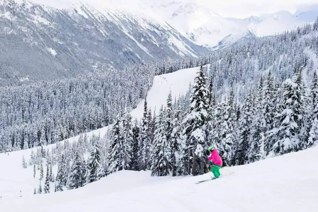 lady skiing down slope in whistler at winter