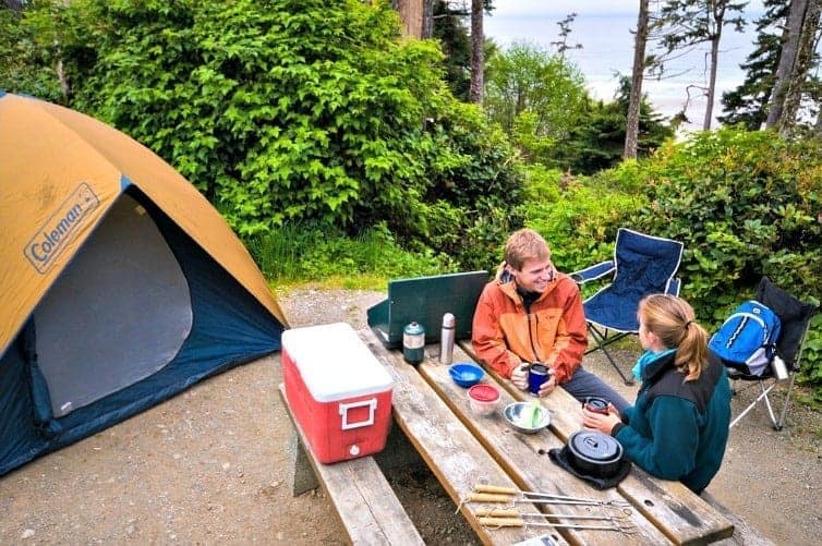 two people sitting at camp table with tent