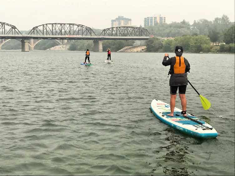 three people paddle boarding on the south Saskatchewan river in summer