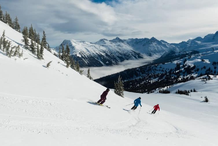 family skiing down slope in whistler