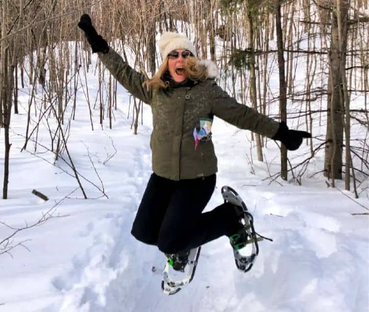 lady jumping with snowshoes in winter