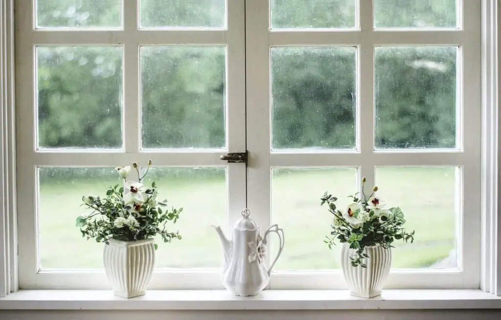 two white vases and watering can at window