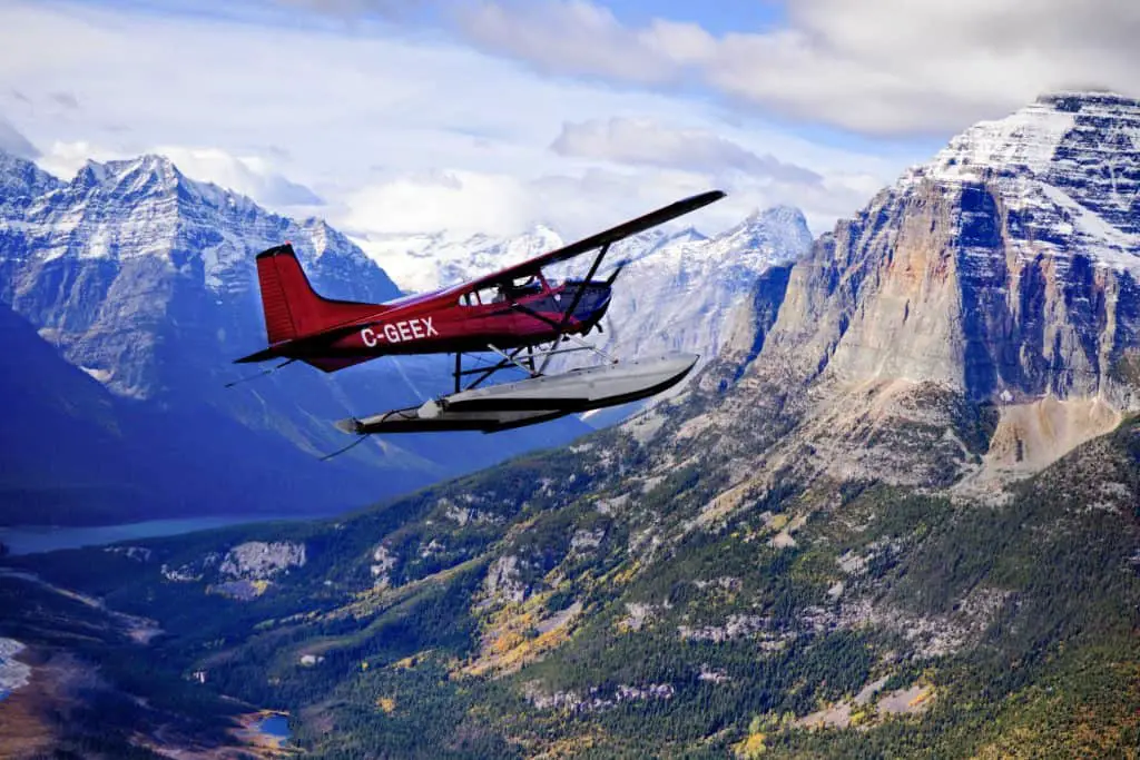 red plane flying over rocky mountains
