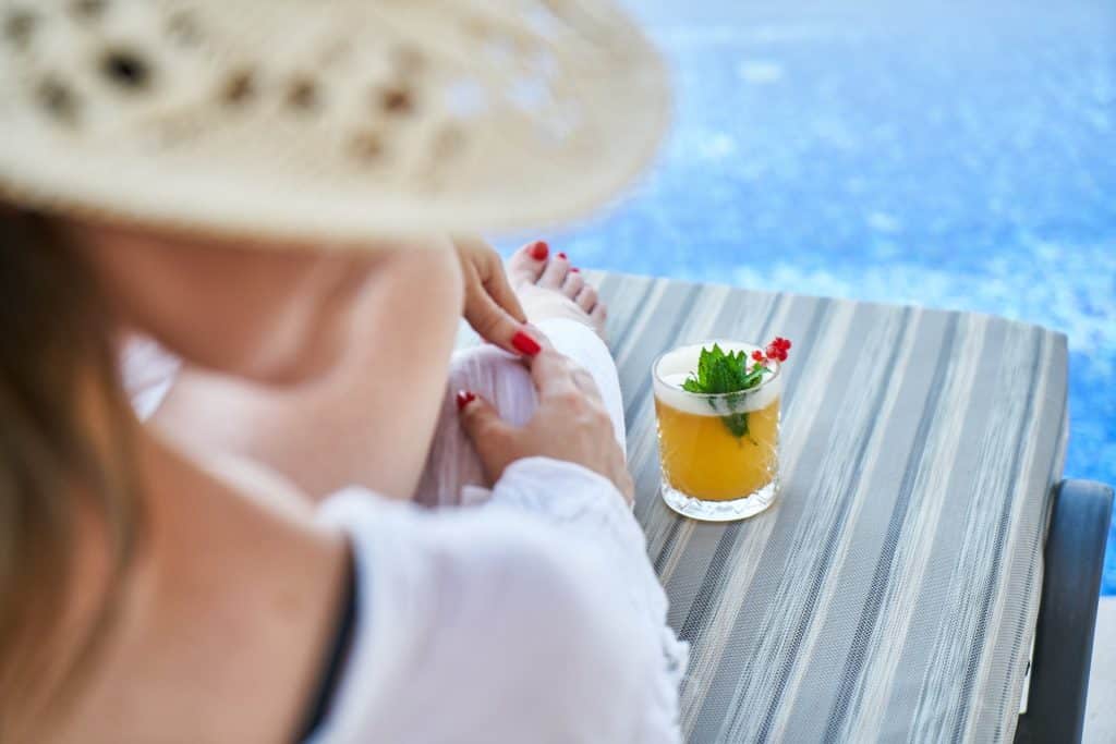 woman by pool with tropical drink
