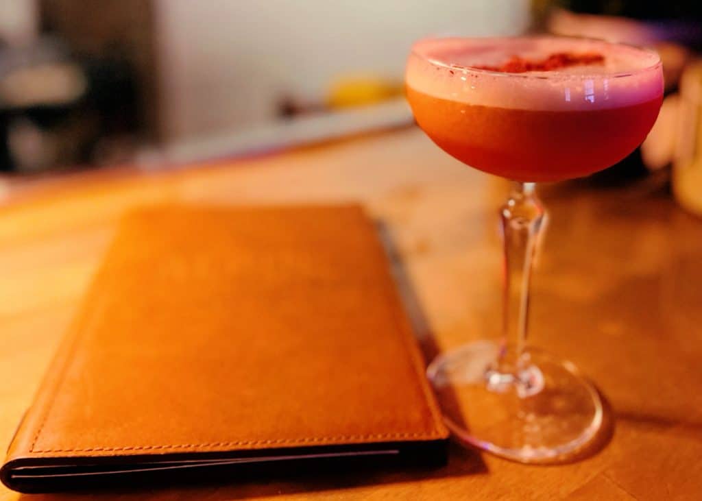 pink cocktail and menu at alpine distilling