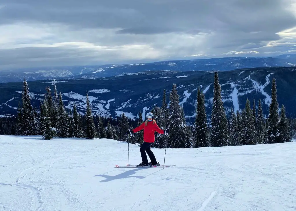 lady in red coat skiing sun peaks