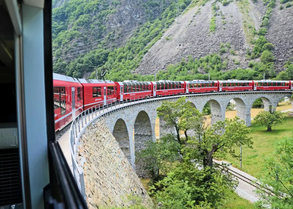 swiss train going over stone bridge