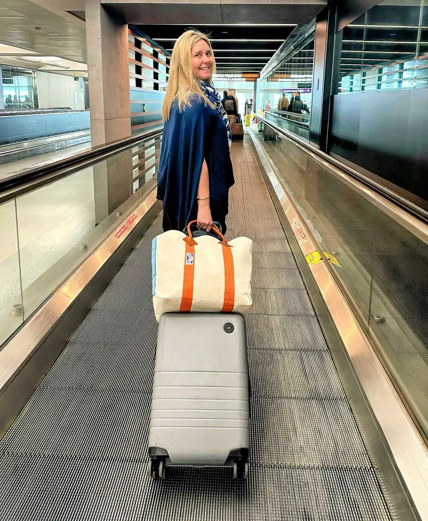 claudia walking with monos suitcase at airport