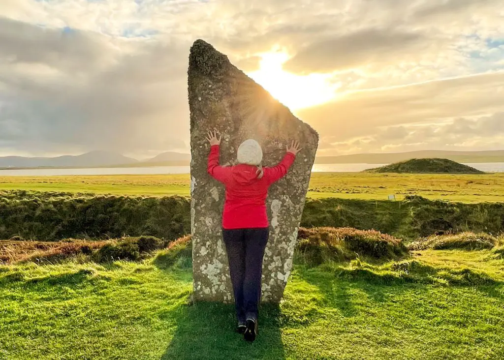 lady in red coat touching stone on ring of brodgar