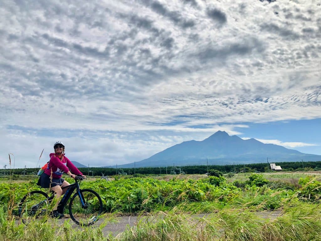 lady in pink jacket cycling with mt rishiri in the background