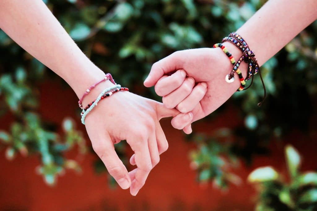two hands wearing friendship bracelets